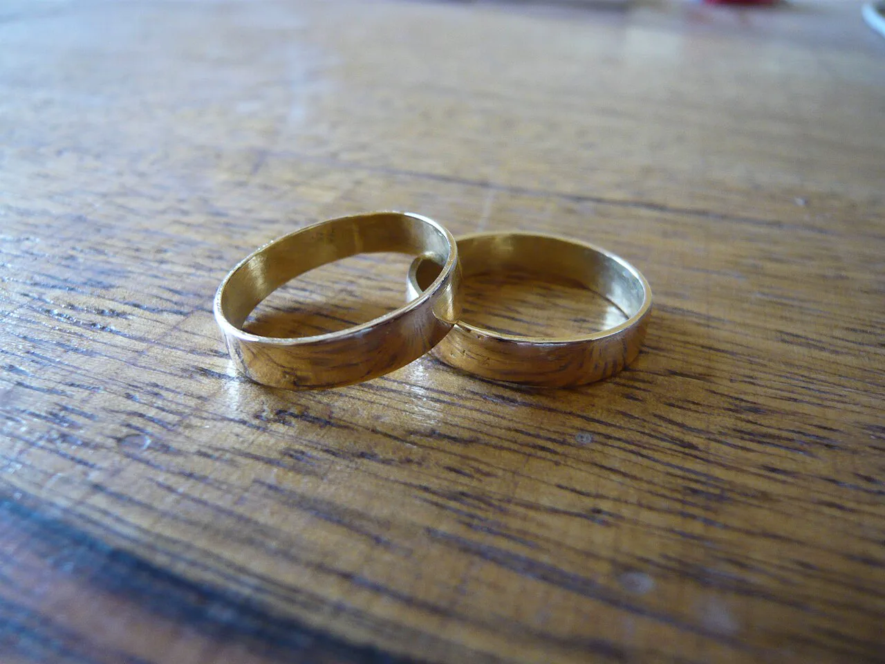 Two plain gold wedding bands lying side by side on a wooden table